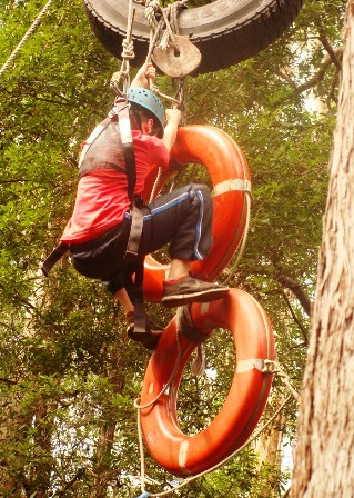 Student with harnass on climbing on tyres